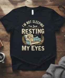Funny "I'm Not Sleeping I'm Just Resting My Eyes" quote on a black t-shirt, featuring a person napping on a