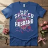 I'm Not Spoiled my HUSBAND Just Loves Me quote with floral heart and lips graphic on a blue t-shirt