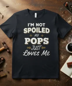 I'm Not Spoiled My Pops Just Loves Me quote in distressed white and gold text on a black t-shirt