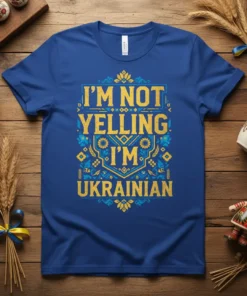 Blue t-shirt with yellow and blue text "I'm Not Yelling I'm Ukrainian" in a decorative font, featuring Ukrainian folk art