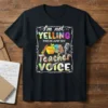 I'm not YELLING THIS IS JUST MY Teacher VOICE quote on a black t-shirt with colorful text and school-related graphics