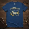 T-shirt with gold text "I'm Not A Gynecologist But I'll Take A Look" and cartoon eyes, stethoscope detail, on navy