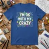 Blue t-shirt with "I'm OK With My Crazy" in colorful, bold lettering and whimsical graphics like lightning bolts and clouds