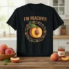 Black t-shirt with "I'M PEACHY!!!" text and a detailed graphic of a sliced peach surrounded by a floral and leaf