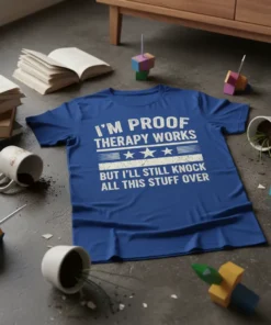 Blue t-shirt with white text: "I'm Proof Therapy Works But I'll Still Knock All This Stuff Over" quote design