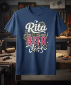 T-shirt with the text "I'm Rita Doing Rita Things" in distressed white and pink lettering, featuring gear graphics