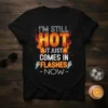 I'm Still Hot It Just Comes In Flashes Now text design with fiery graphics on a black t-shirt