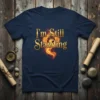 I'm Still Standing quote with a fiery phoenix graphic on a navy blue t-shirt
