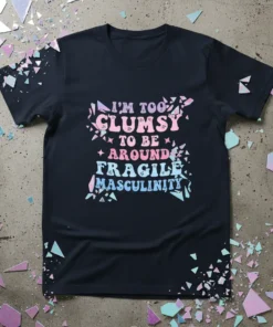 Black t-shirt with "I'm Too Clumsy To Be Around Fragile Masculinity" text in pastel gradient, featuring a shattered effect graphic