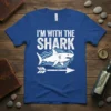 Blue t-shirt with white text "I'M WITH THE SHARK" and a graphic of a shark with waves and an arrow