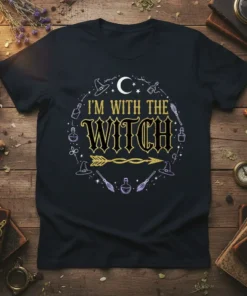 I'm With The Witch t-shirt featuring gold and black text with witchy graphics like hats, brooms, and potions