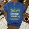 I'm a Lucky Music Teacher text design with green arrows and musical notes on a blue t-shirt