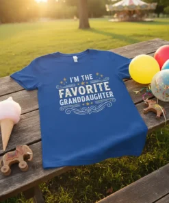 Blue t-shirt with white distressed text that reads "I'm the Favorite Granddaughter" with decorative stars and swirls