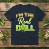 I'm The Real Dill funny pickle quote on a dark t-shirt with a cartoon pickle character giving a thumbs up