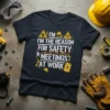 Dark t-shirt with white text "I'm The Reason For Safety Meetings At Work" and construction-themed graphics