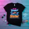 Black t-shirt with neon text: "I'M THE Yungest Sister" above a cruise ship graphic, with "CRUISE RULES DON'T APPLY TO