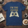 I'm The Zayde t-shirt design with gold text and a graphic of hands holding a vintage locket with a child's