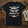 T-shirt with text "Immigrants Are Not Criminals, But The President Is" and a graphic of the US Capitol behind barbed