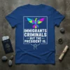Blue t-shirt with geometric colorful bird graphic and white text: "IMMIGRANTS CRIMINALS BUT THE PRESIDENT IS."