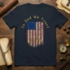 In God We Trust 1776 text above a distressed vintage American flag graphic on a navy blue t-shirt
