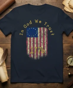 In God We Trust 1776 text above a distressed vintage American flag graphic on a navy blue t-shirt