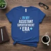 Blue t-shirt with white and yellow text reading "In My Assistant Superintendent Era" and featuring a lightning bolt and apple