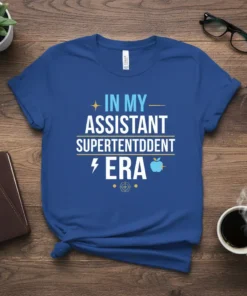Blue t-shirt with white and yellow text reading "In My Assistant Superintendent Era" and featuring a lightning bolt and apple