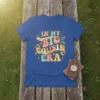 Retro style t-shirt with colorful text "In My Big Cousin Era" and decorative elements, featuring a big cousin quote