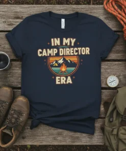 In My Camp Director Era text design with mountain and campfire graphic, retro style, on a navy t-shirt