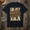 Retro "In My Cool Grandpa Era" text design with vintage goggles graphic on a navy t-shirt