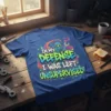 Blue t-shirt with bold graffiti-style text "In My Defense I Was Left Unsupervised" and a mischievous blue goblin holding a