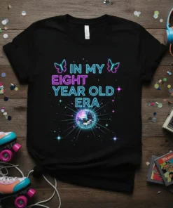 In My Eight Year Old Era text with neon butterflies and disco ball graphic on black t-shirt