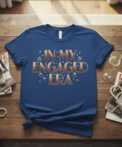 Text "In My Engaged Era" in rose gold glitter font with diamond and ring graphics on a royal blue t-shirt