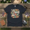 In My Flower Girl Era text with colorful retro flowers and butterflies graphic on a black t-shirt