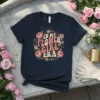 In My Flower Girl Era text with floral graphics on a navy t-shirt