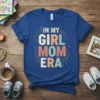 In My Girl Mom Era text design with playful stars and constellations, featuring pastel colored letters on a blue t-shirt