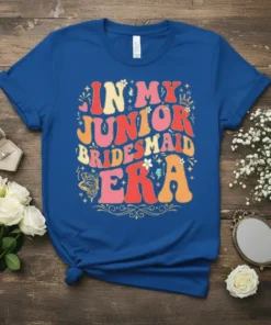Retro style "In My Junior Bridesmaid Era" text design with colorful wavy font and floral accents on a blue t-shirt