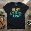 In My Let Them ERA text design on a black t-shirt, featuring yellow and teal typography with a small heart
