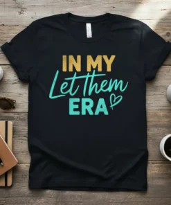 In My Let Them ERA text design on a black t-shirt, featuring yellow and teal typography with a small heart