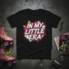 Black t-shirt with white and pink text "IN MY LITTLE ERA" in a bold, retro comic book style, surrounded by
