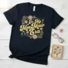 Navy t-shirt with "In My Mee Maw Era" in gold glitter font, surrounded by pink and white flowers