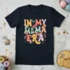 Retro "In My Mema Era" text with colorful floral and butterfly graphics on a navy t-shirt