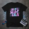 Black t-shirt with "In My Milf Era" in retro pink and blue gradient font, decorated with neon lines and small