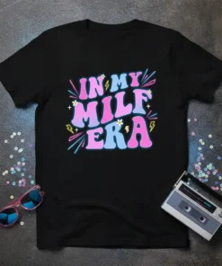 Black t-shirt with "In My Milf Era" in retro pink and blue gradient font, decorated with neon lines and small