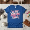 In My Mom Era text design with pink gradient letters and star and moon graphics on a royal blue t-shirt