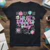 Groovy "In My Parapro Era" text design with school icons like books, globe, and apple on a black t-shirt