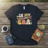 Retro "In My Retirement Era" text design with icons like a book, globe, coffee cup, and hiking boot on a
