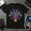 Black t-shirt with "in my SCRUB LIFE era" text in neon colors, surrounded by medical symbols like caduceus and syringes