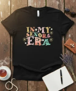 In My Señora Era text design with colorful typography and small floral accents on a black t-shirt