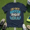 Navy t-shirt with "In My Soccer Mom Era" text and a soccer ball graphic, featuring lightning bolt accents and stars